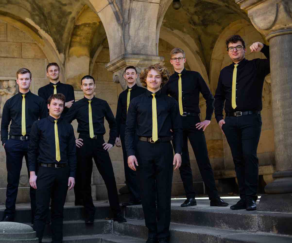 Acht Junge Männer mit Gelben Krawatten auf den Stufen einer Kirche